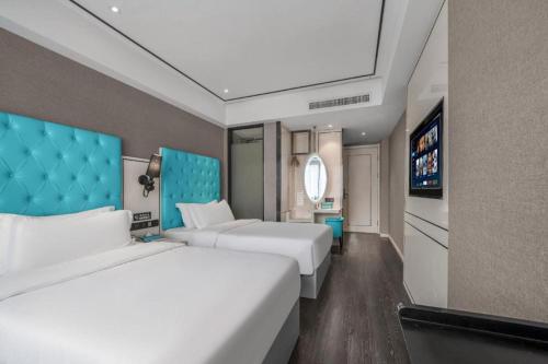 a hotel room with two beds and a tv at Xana Hotelle Chongqing Jiefangbei Center Branch in Chongqing