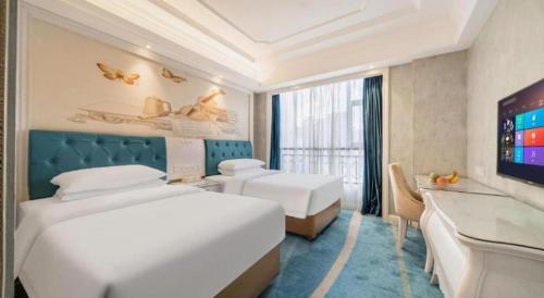 a hotel room with two beds and a flat screen tv at Vienna Hotel Guiyang Jiaxiulou Jichang Road in Guiyang