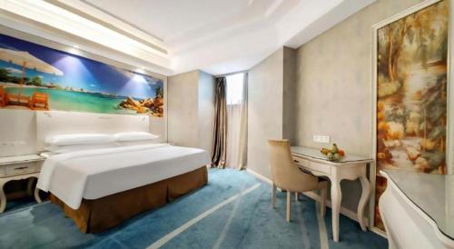 a bedroom with a large bed and a desk in it at Vienna Hotel Guiyang Jiaxiulou Jichang Road in Guiyang
