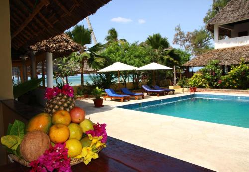 eine Schale Obst auf einem Tisch neben einem Pool in der Unterkunft Blu Marlin Village in Kiwengwa