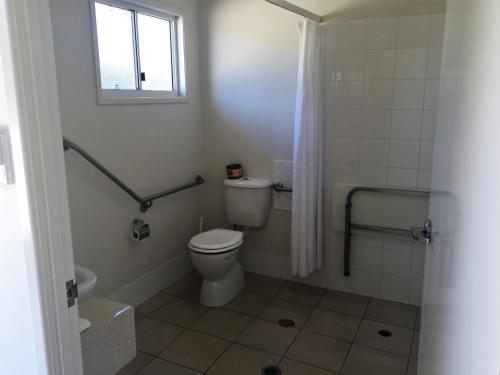 ein kleines Bad mit einem WC und einem Fenster in der Unterkunft Swag Motel in Middlemount
