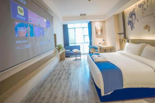 a hotel room with a large bed and a projection screen at Kyriad Marvelous Hotel Xiangyin Bus Station in Xiangyin