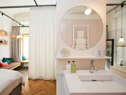 a white bathroom with a sink and a mirror at grätzlhotel Karmelitermarkt in Vienna