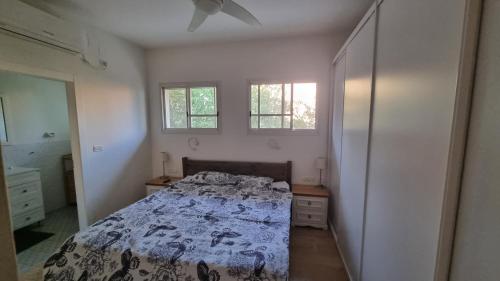 a bedroom with a bed and two windows at וילה במושב בנוף מושלם כל השנה in Moledet
