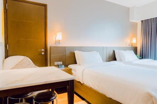 a hotel room with two beds and a table at The Residences at Novotel Tower in Manila