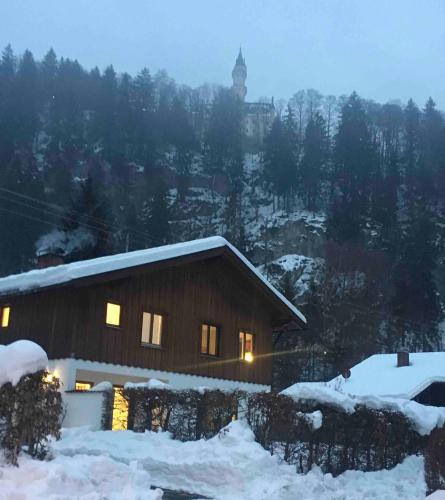 a house with lights on in the snow at King Ludwig's Old Neighbour in Schwangau