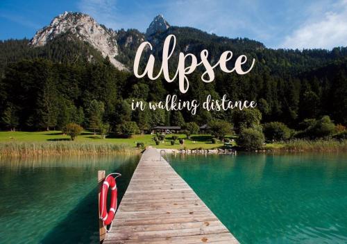 a wooden bridge over a lake with mountains in the background at King Ludwig's Old Neighbour in Schwangau