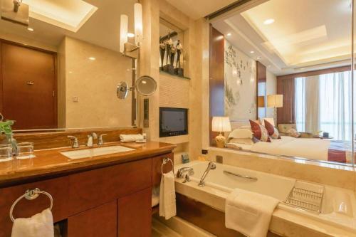 a bathroom with a tub and a large mirror at Dezhou Regal Kangbo Hotel in Dezhou