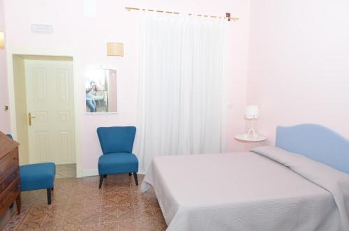 a bedroom with a bed and two blue chairs at B&B Casa D'alleri in Siracusa