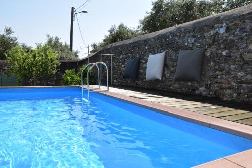 a swimming pool with a stone wall and blue water at Bouganville in Seravezza