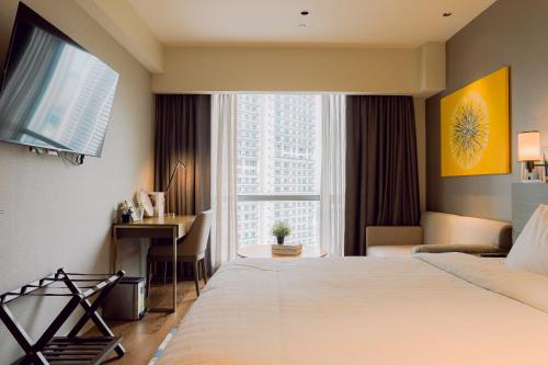 a hotel room with a bed and a desk and a window at The Residences at Novotel Tower in Manila
