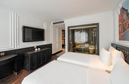 a living room with a white couch and a tv at Luxe Paradise Premium Hotel and Spa in Hanoi