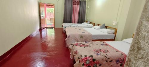 a hotel room with three beds and red floors at Nisarga Coorg Home Stay in Somvārpet
