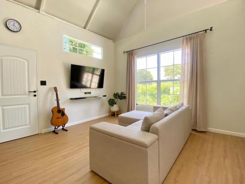 a living room with a couch and a guitar at Small Hours Homestead Living Khaoyai in Ban Rai