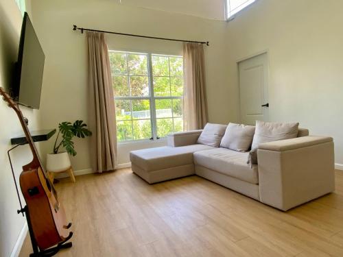 a living room with a white couch and a guitar at Small Hours Homestead Living Khaoyai in Ban Rai