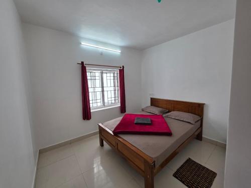 a room with a bed with a red blanket on it at SRB Cottages in Ooty
