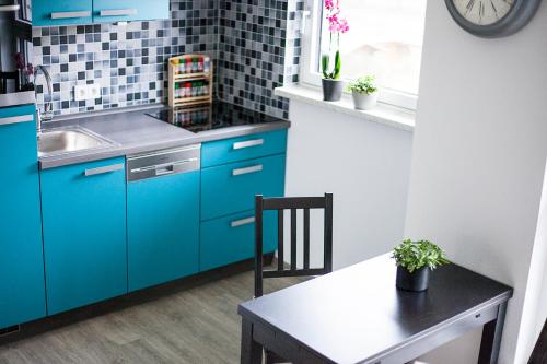 cocina con armarios azules, mesa y reloj en Hoofer Apartments, en Schauenburg