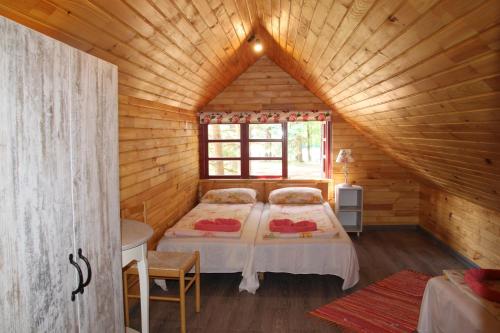 a bedroom with two beds in a wooden cabin at Vērbeļnieki in Pērkone