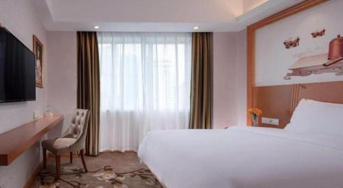 a hotel room with a bed and a desk and a window at Out Sky Hotel in Huizhou
