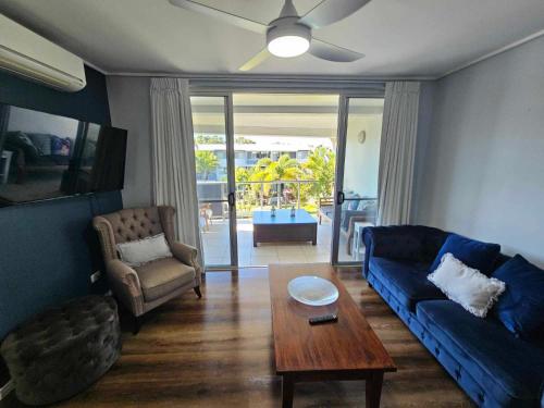 a living room with a blue couch and a table at Large Pool Newly Renovated Apartment Walk to Whale watching and beaches in Urangan