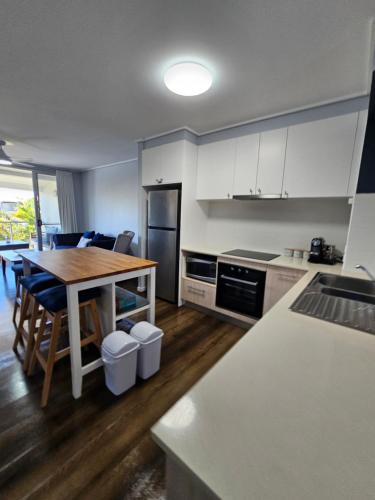 a kitchen with a table and a kitchen with white cabinets at Large Pool Newly Renovated Apartment Walk to Whale watching and beaches in Urangan