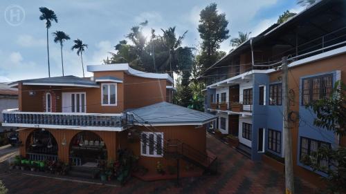 eine Gruppe von Gebäuden mit Palmen im Hintergrund in der Unterkunft Harmony Inn in Wayanad