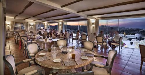 a restaurant with tables and chairs with people sitting around them at Hotel Li Finistreddi in Cannigione