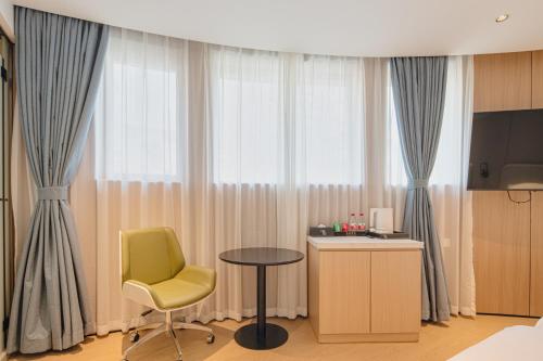 a room with a chair and a table and a window at Dayin Garden Hotel -People's Square & Nanjing Road-Large Social Area -Bar -Café -Gym -Free Laundry Luggage Storage -24H Front Desk-English Service in Shanghai