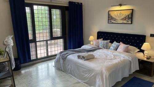 a bedroom with a large white bed with two windows at Taj Waves - A Luxurious Pool Villa in Agra