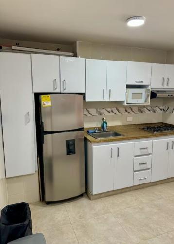 a kitchen with a stainless steel refrigerator and white cabinets at leslies apartamentos in Cartagena de Indias