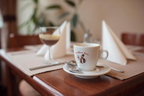 a cup of coffee and a glass of wine on a table at Penzion Nad Oborou in Hradec Králové