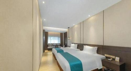 a bedroom with a large white bed with a blue blanket at H Life Hotel Nanshan Branch in Shenzhen