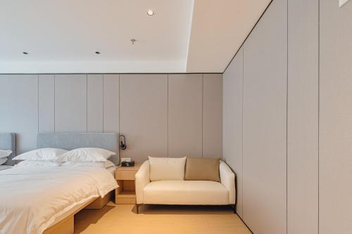 a bedroom with a bed and a chair at Dayin Garden Hotel -People's Square & Nanjing Road-Large Social Area -Bar -Café -Gym -Free Laundry Luggage Storage -24H Front Desk-English Service in Shanghai