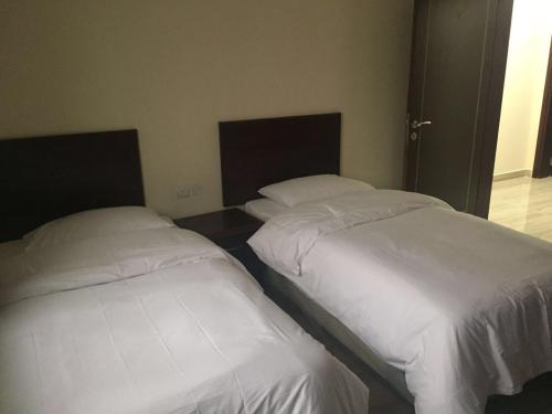 two beds sitting next to each other in a room at Al Noor Saadah Furnished Apartments in Salalah