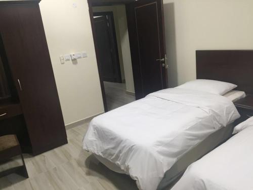 a bedroom with two beds and a mirror at Al Noor Saadah Furnished Apartments in Salalah