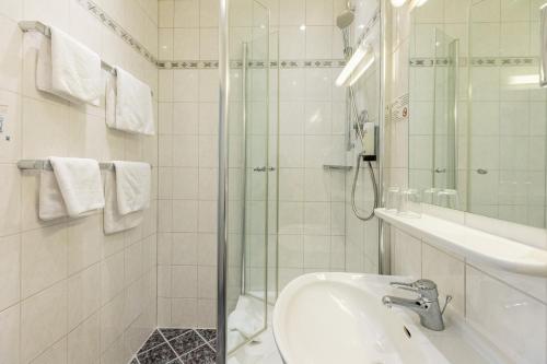 a white bathroom with a sink and a shower at Hotel West an der Bockenheimer Warte in Frankfurt/Main