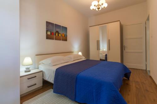 a bedroom with a bed with a blue bedspread at Apartments Svilan in Trogir