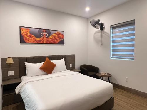 a bedroom with a large white bed and a chair at Swan Boutique Hotel in Ho Chi Minh City
