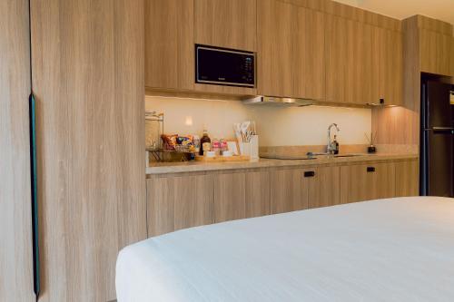a kitchen with wooden cabinets and a bed in a room at The Residences at Novotel Tower in Manila