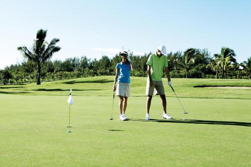 a man and a woman standing on a golf course at Shanti Maurice Resort & Spa in Bel Ombre