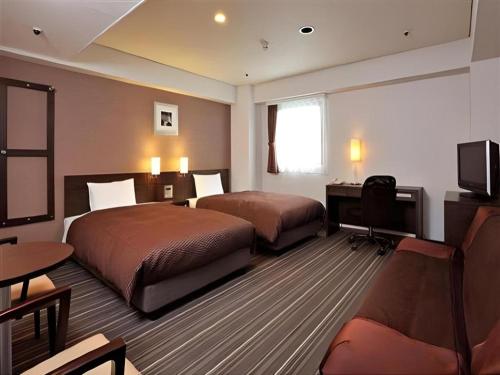 a hotel room with two beds and a television at Daini Fuji Hotel in Nagoya