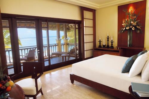 a bedroom with a bed and a balcony with the ocean at Shanti Maurice Resort & Spa in Bel Ombre