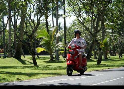 a man riding a red scooter down a street at Hotel Longteng in Sigiriya
