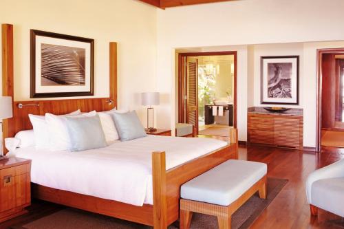 a bedroom with a large white bed and a chair at Shanti Maurice Resort & Spa in Bel Ombre