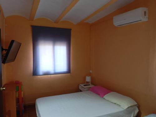 a bedroom with a white bed and a window at Casa para fines de semana cuevas del turche buñol in Buñol