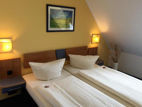 two beds in a room with two lamps on the wall at Hotel Ambiente in Halberstadt