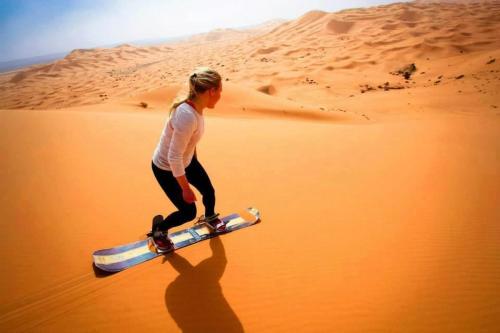 a woman walking in the desert with a skateboard at Auberge Sahara Garden in Lac Yasmins