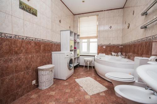 a bathroom with a tub and a toilet and a sink at Ginger Apartment Riga in Rīga