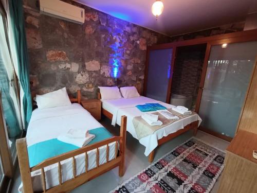 two beds in a room with a stone wall at Kabak Armes Otel in Fethiye
