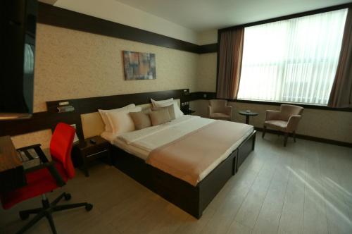 a bedroom with a large bed and a red chair at Wes Hotel in Kocaeli
